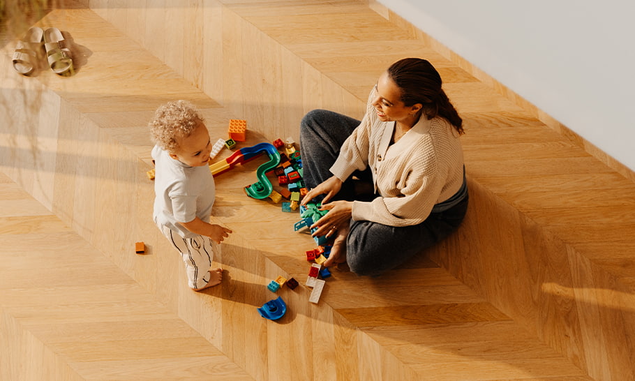 nainen ja lapsi istumassa kalanruotokuvioisella lattialla